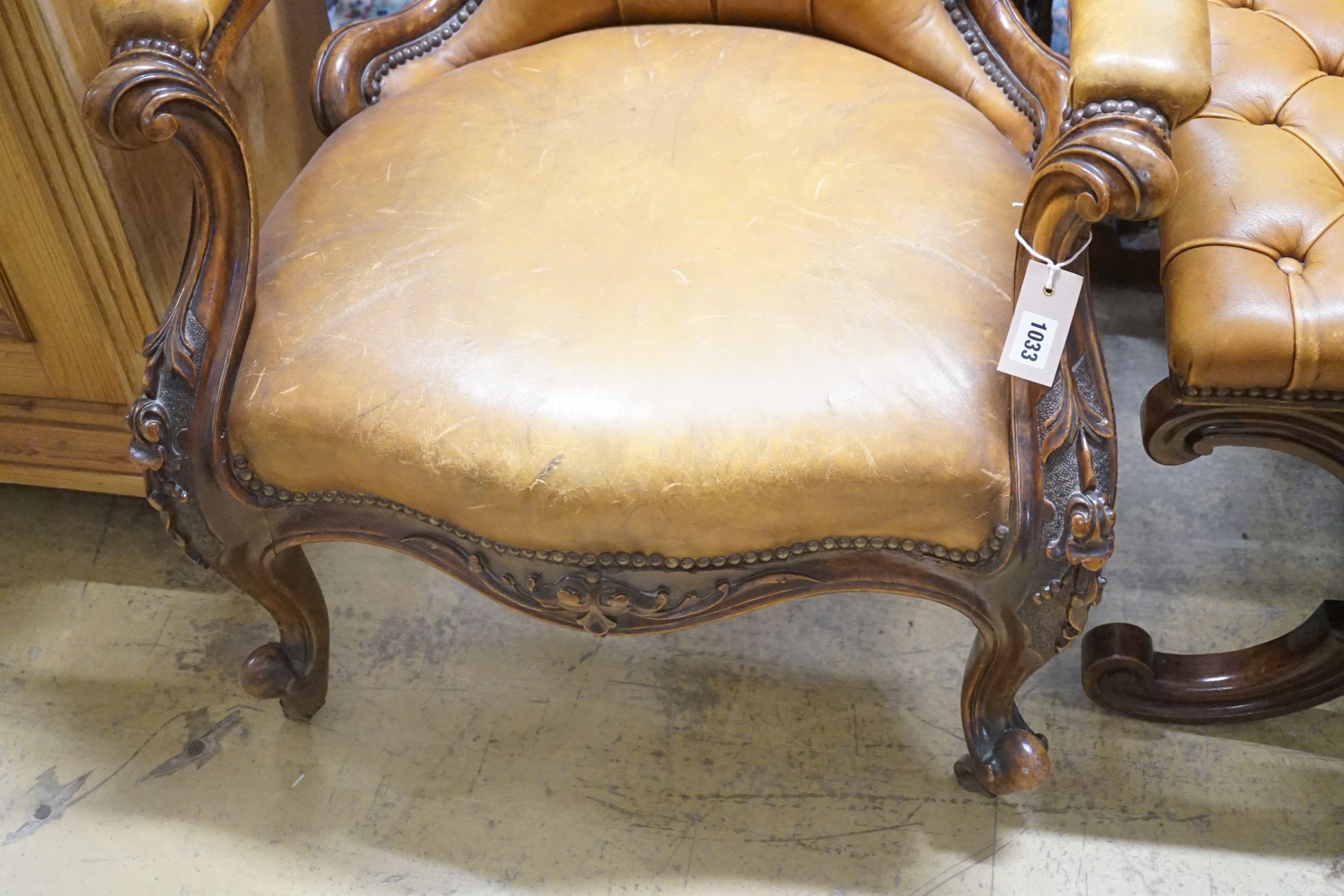 A Victorian carved walnut spoonback open armchair, upholstered in buttoned brown leather, width 69cm depth 66cm height 99cm